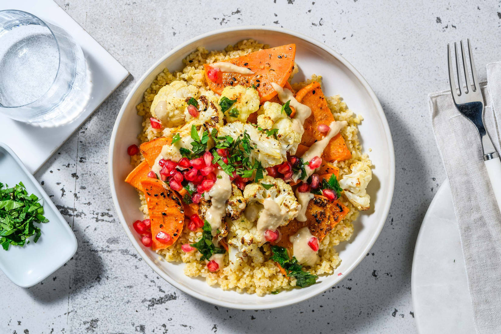 Légumes rôtis garnis de grenade et houmous