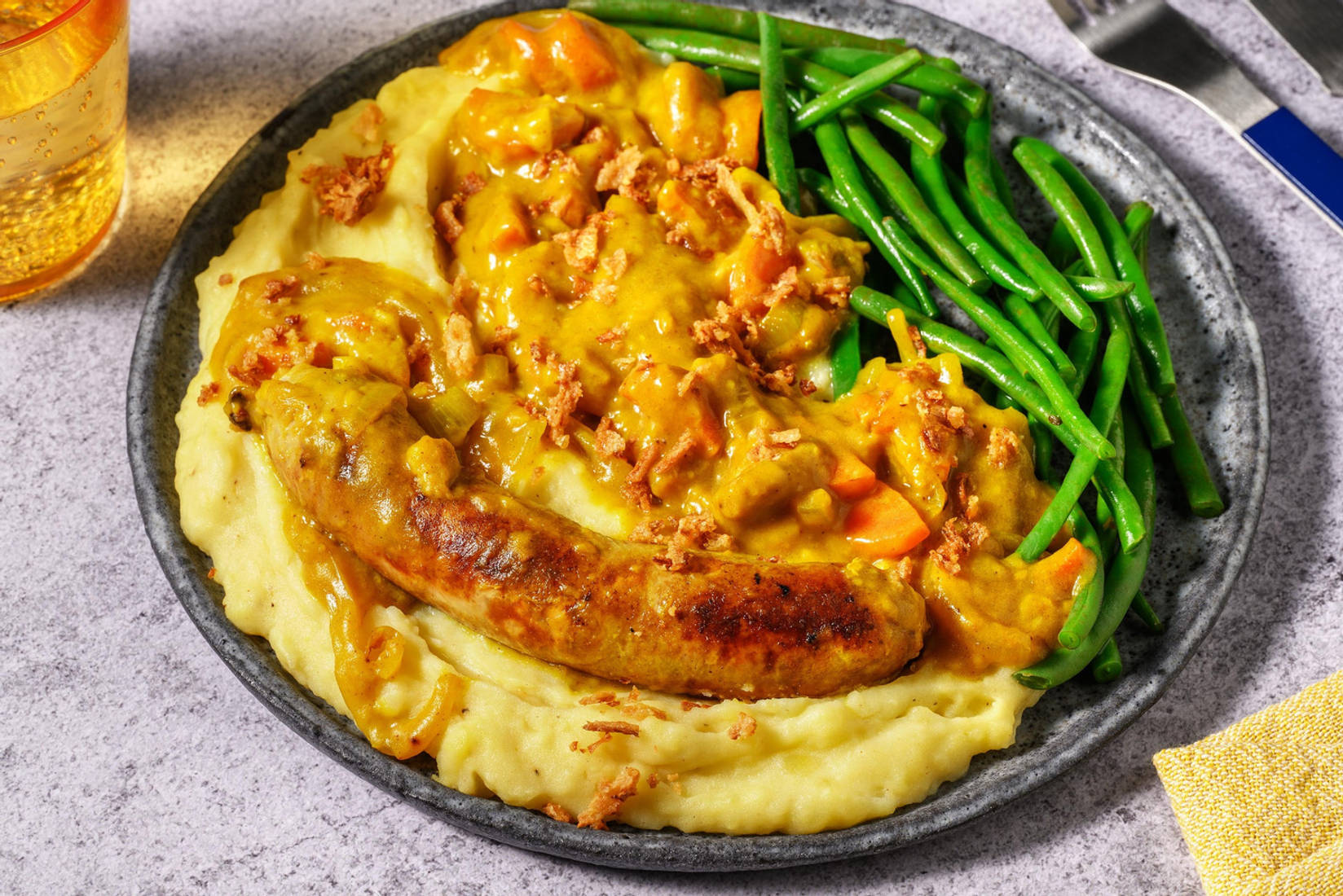 Varkensworst in kerriesaus met gefrituurde uitjes