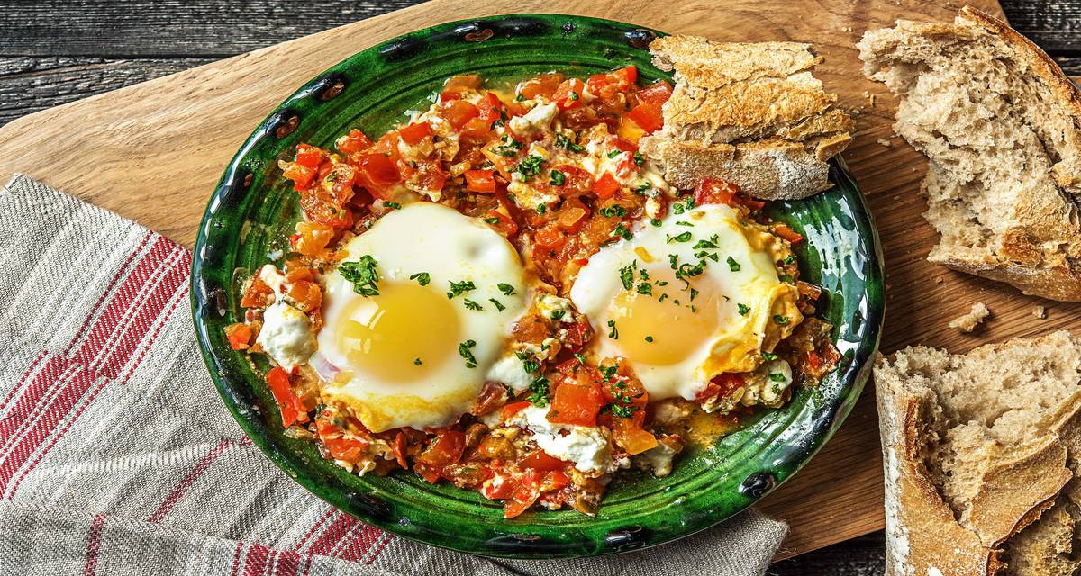 Traditionele shakshuka met ei, geitenkaas en speltbaguette Avec du chèvre et une baguette d’épeautre