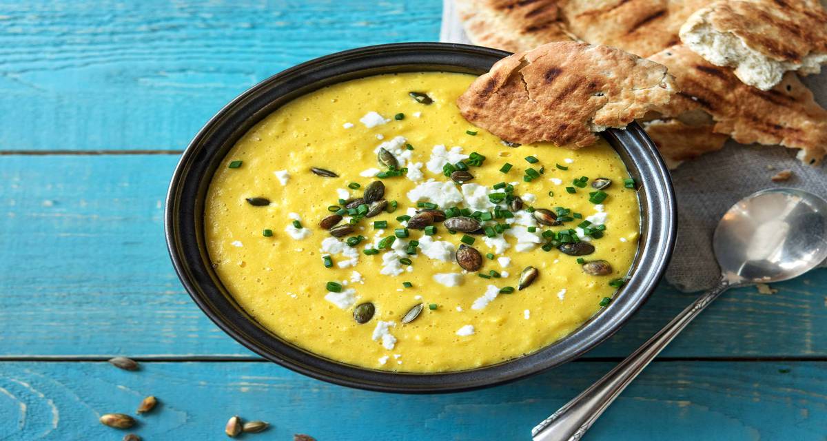 Soupe au poivron jaune et au maïs avec feta, graines de courge, pain naan Légèrement relevée grâce au cumin et à la coriandre moulue