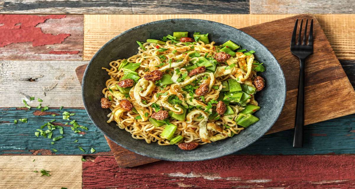 Nouilles thaïes aux tranches d'omelette et aux cacahuètes caramélisées Avec des haricots plats et de la coriandre