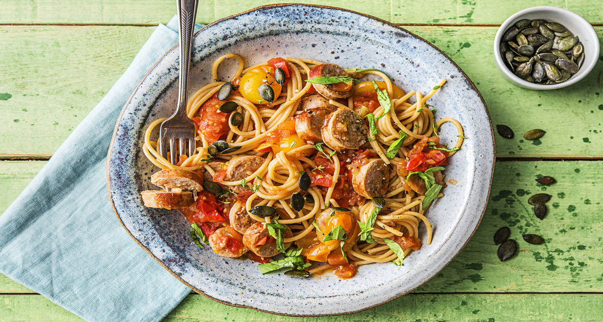 Spaghetti complets et merguez de boeuf Avec des tomates colorées et des graines de courge