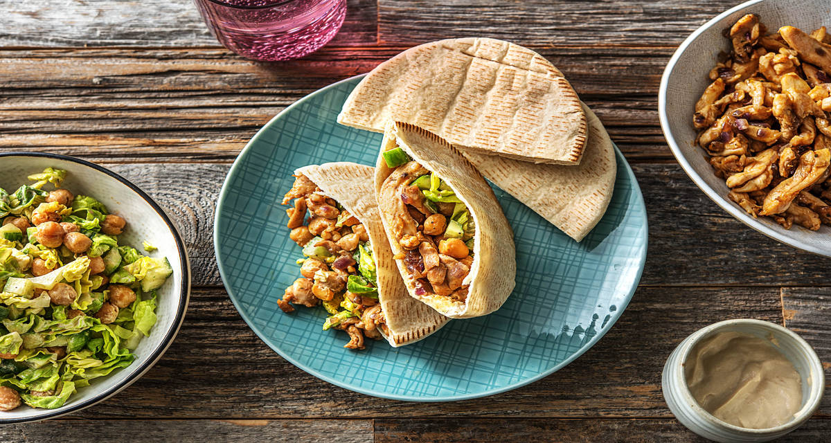 Pitas au poulet épicé et salade Avec des pois chiches grillés, du concombre et une sauce au yaourt et au tahini