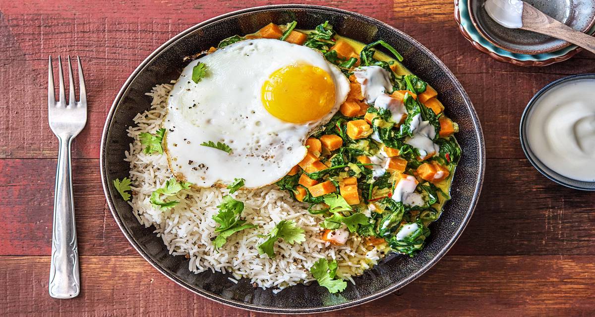 Curry d'épinards et de patates douces, œuf au plat et yaourt Avec du piment rouge et de la coriandre fraîche