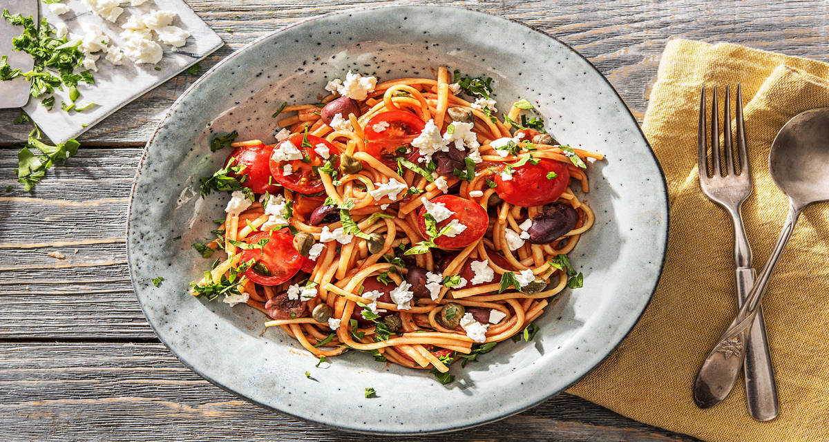 Linguine aux tomates cerises, aux câpres et aux olives Avec du persil frais et de la feta