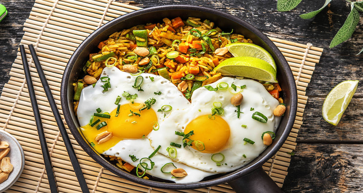 Nasi goreng et œuf au plat Avec du citron vert, des cacahuètes et de la coriandre