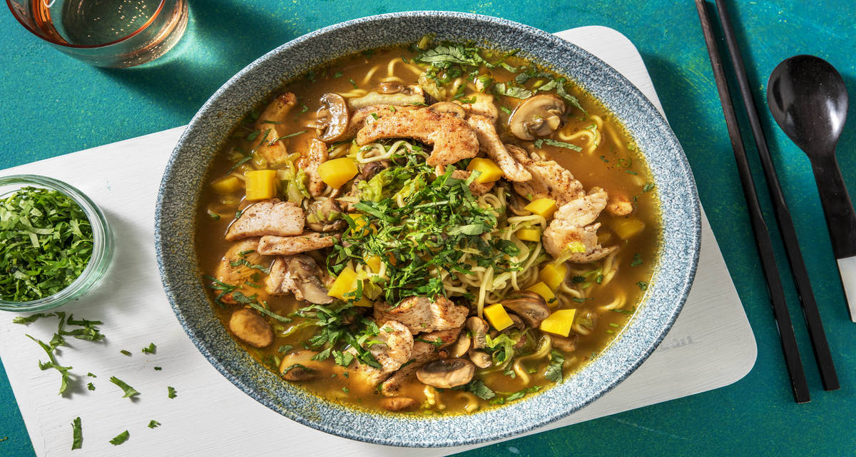Soupe de nouilles à la thaïlandaise au poulet et à la carotte jaune accompagnée de de champignons blonds, de pe-tsaï (ou chou chinois) et de coriandre