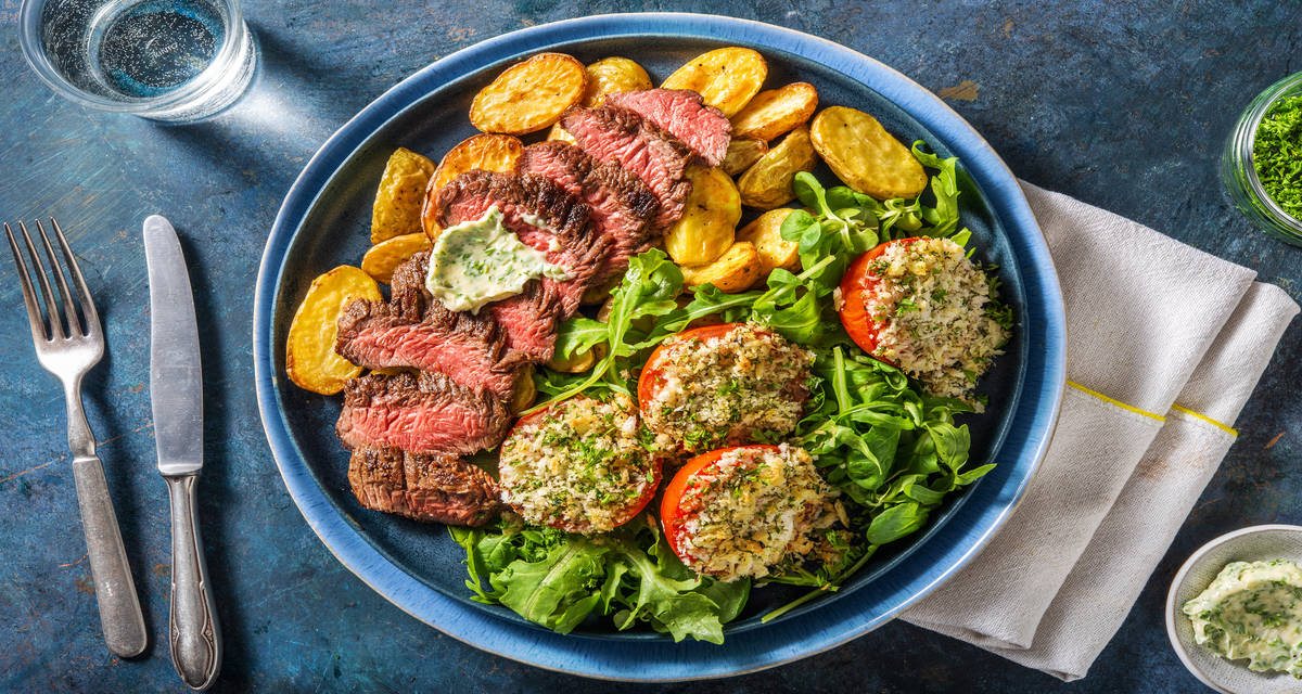 Bavette et beurre aux fines herbes accompagnée de tomates au four, d'une salade et de grenailles