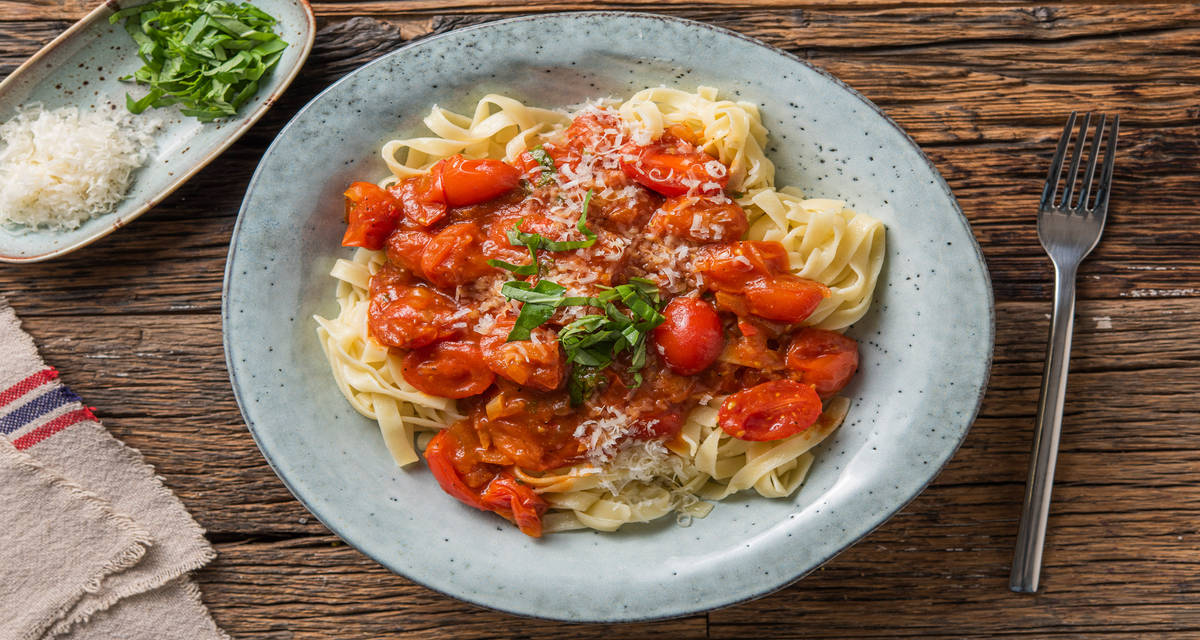 Tagliatelle fraîches et tomates cerises servies avec du basilic et du fromage italien