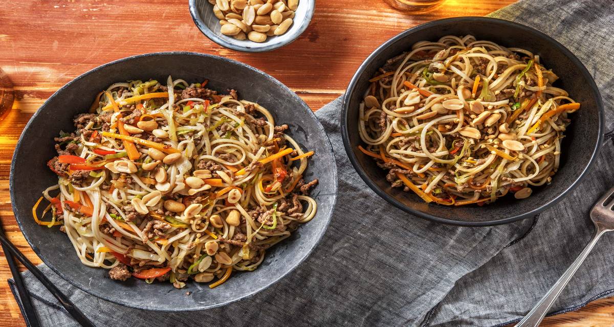 Nouilles et bœuf haché à l'asiatique servies avec des légumes sautés et des cacahuètes croquantes