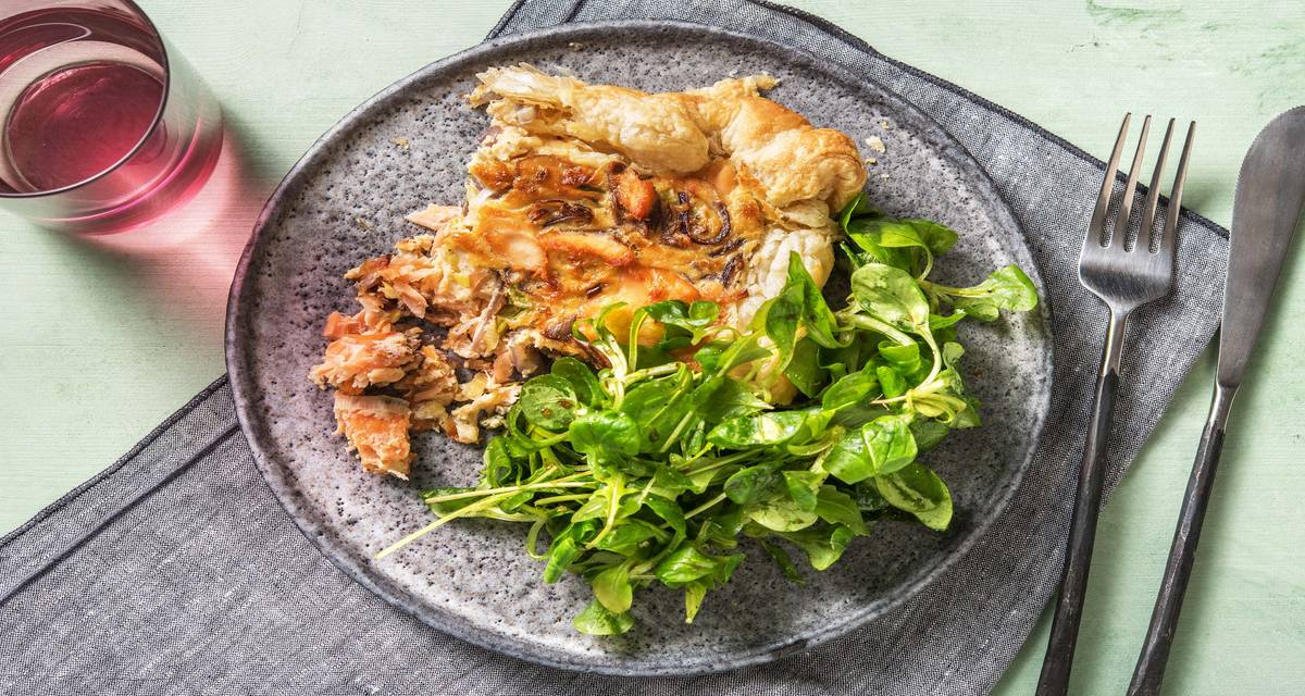 Quiche aux lardons de saumon avec du fromage mi-vieux et servie avec une salade