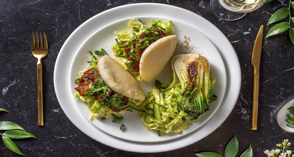 Bao bun au filet de porc servi avec des concombres aigres-doux et du pak-choï à la sauce poisson
