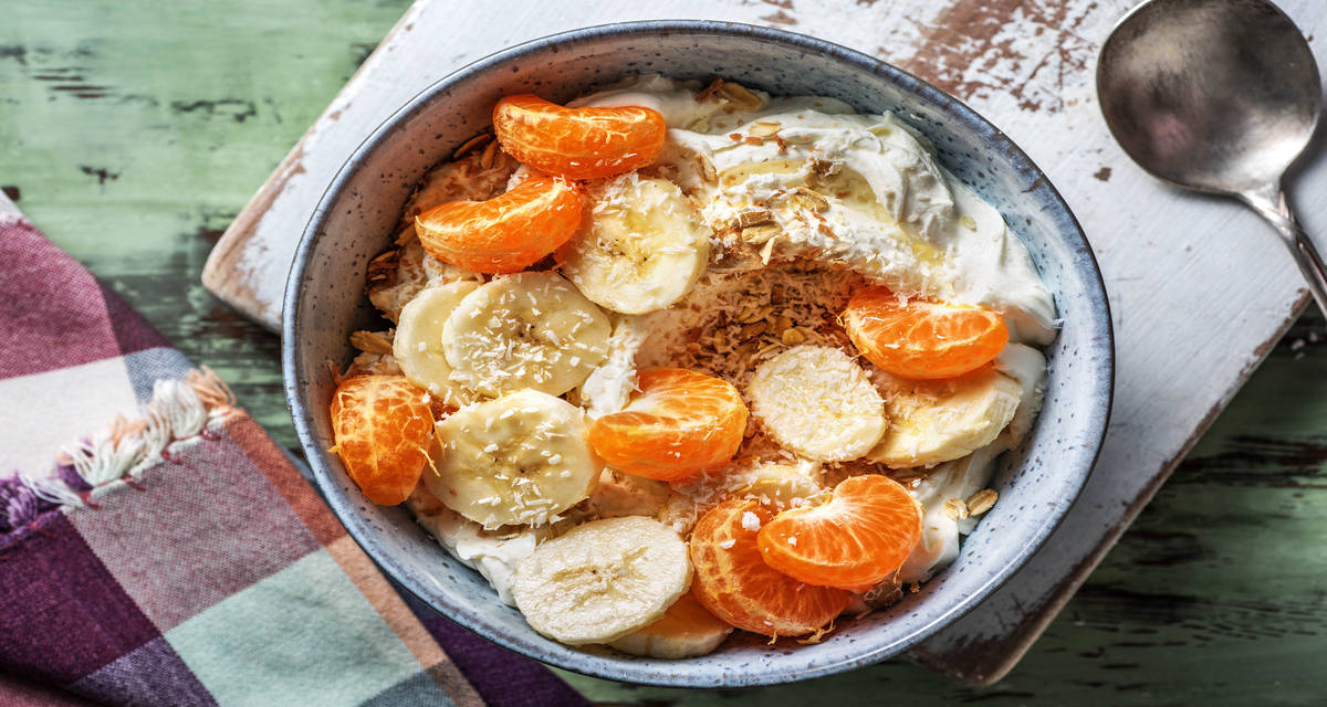 Fromage blanc à la banane avec de la mandarine, de la noix de coco râpée et de muesli