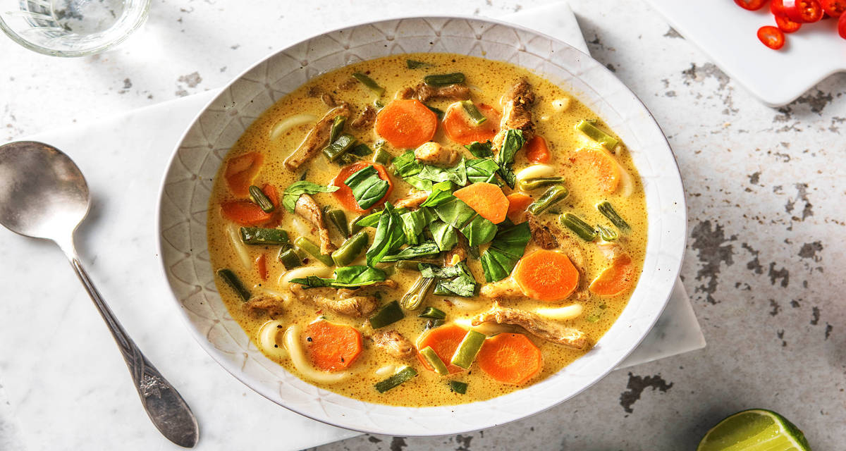 Soupe de nouilles au poulet et lait de noix de coco assaisonnée de citronnelle, de basilic et citron vert