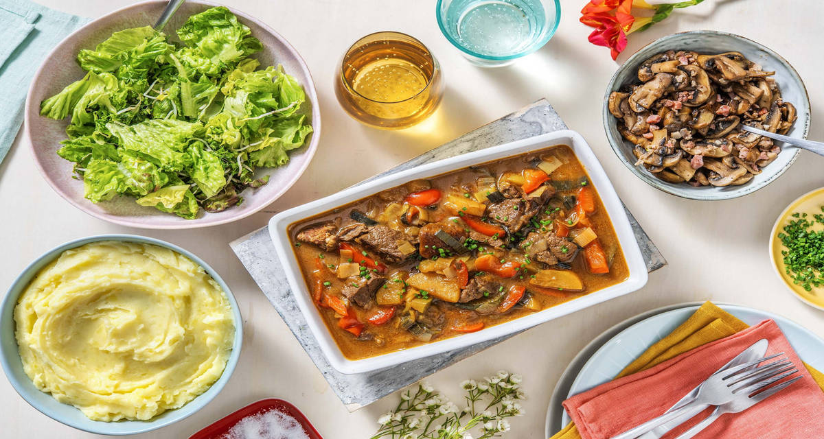 Mijoté de veau et purée de pommes de terre servis avec des champignons aux lardons et une salade