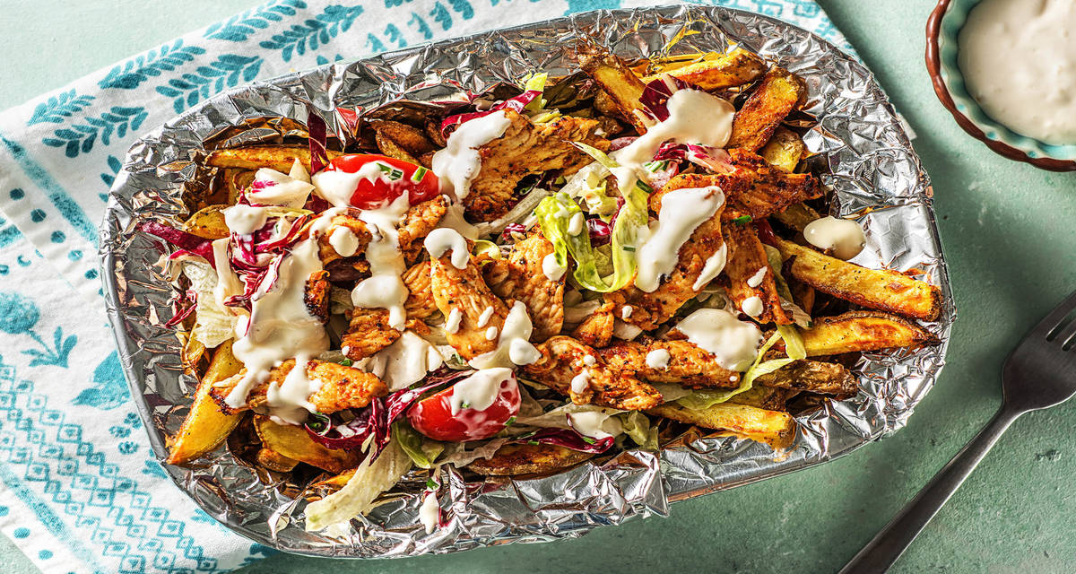 Gyros de poulet avec des frites maison servi avec une mayonnaise à l'ail et une salade composée