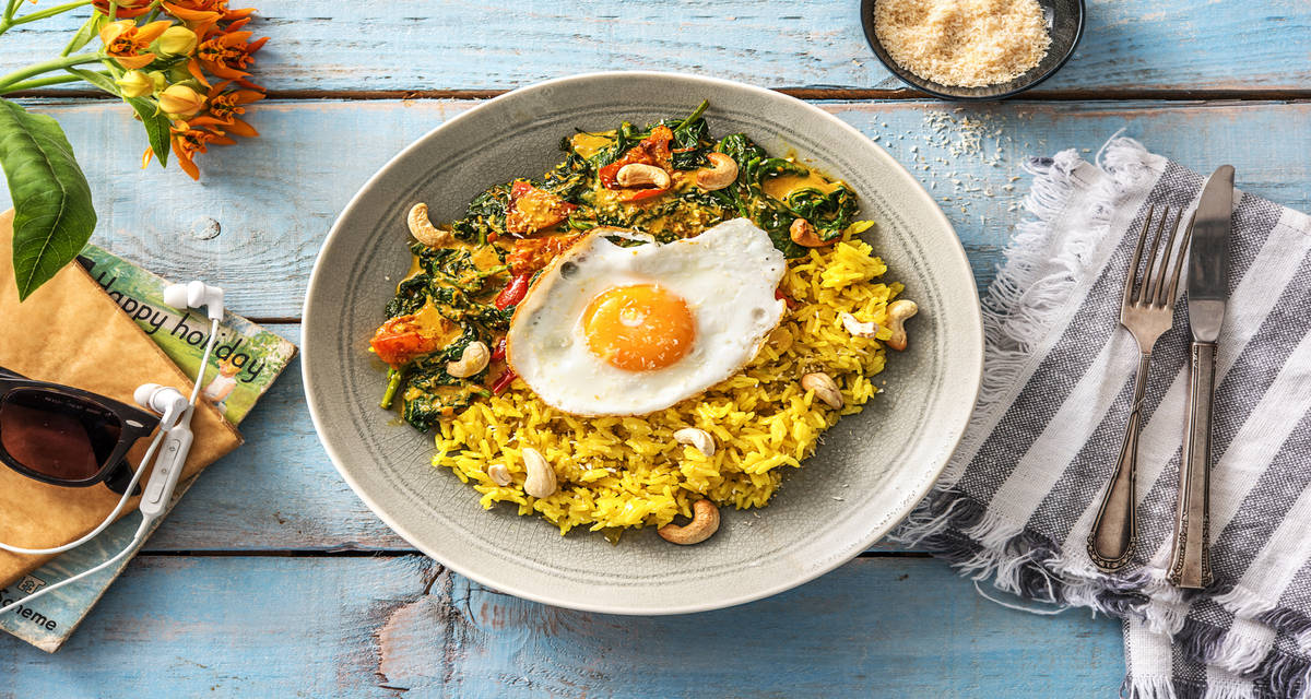 Curry d'épinards & riz au curcuma avec un oeuf au plat, des noix de cajou et un riz au curcuma