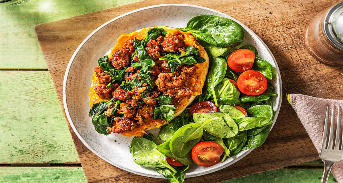 Pizza au bœuf haché, yazzara & épinards sur naan servie avec une salade aux tomates