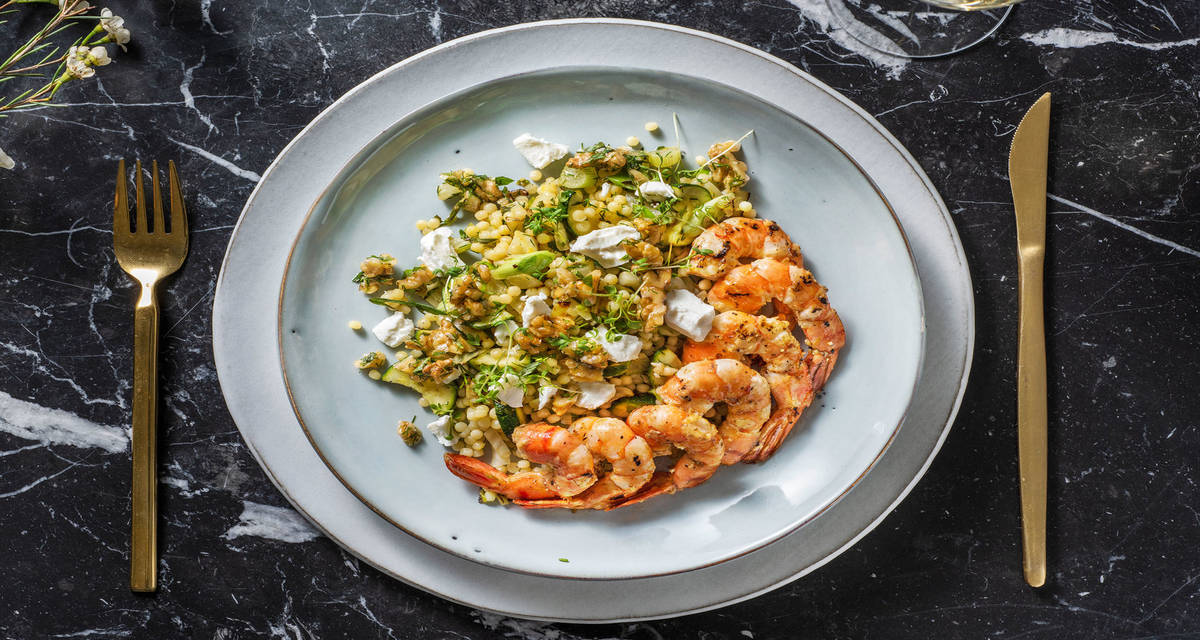 Crevettes poêlées au citron & à l'ail avec du couscous perlé garni de chèvre frais et d'herbes
