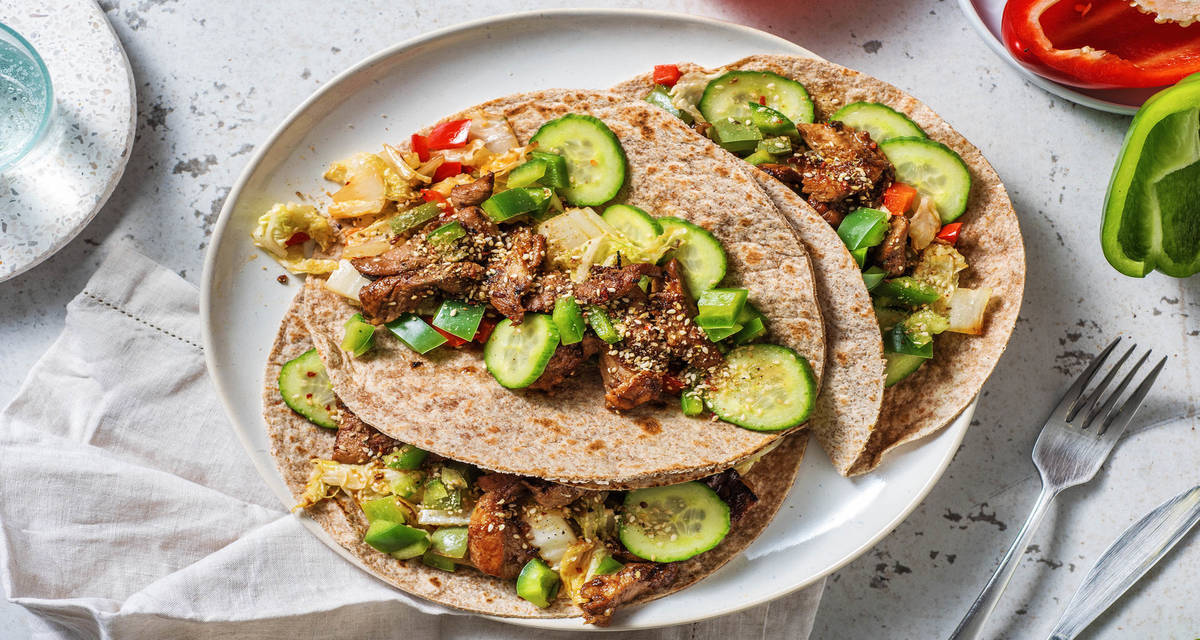 Mini tortillas au porc sauce sucrée salée avec des légumes sautés et des pickles de concombre