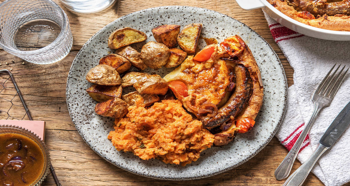 Britse Toad In a Hole met wildzwijn-rundersaucijs en jus accompagnés de pommes de terre rissolées et d’une purée de carottes
