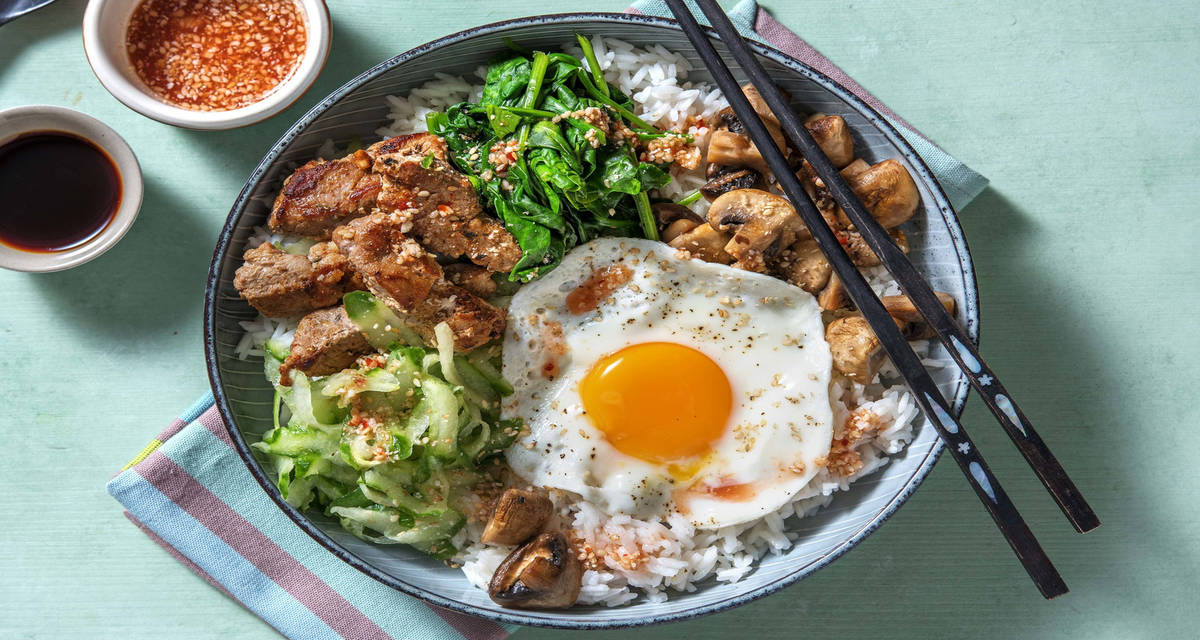 Bibimbap coréen au filet de porc émincé accompagné de légumes crus et sautés et d’un œuf au plat