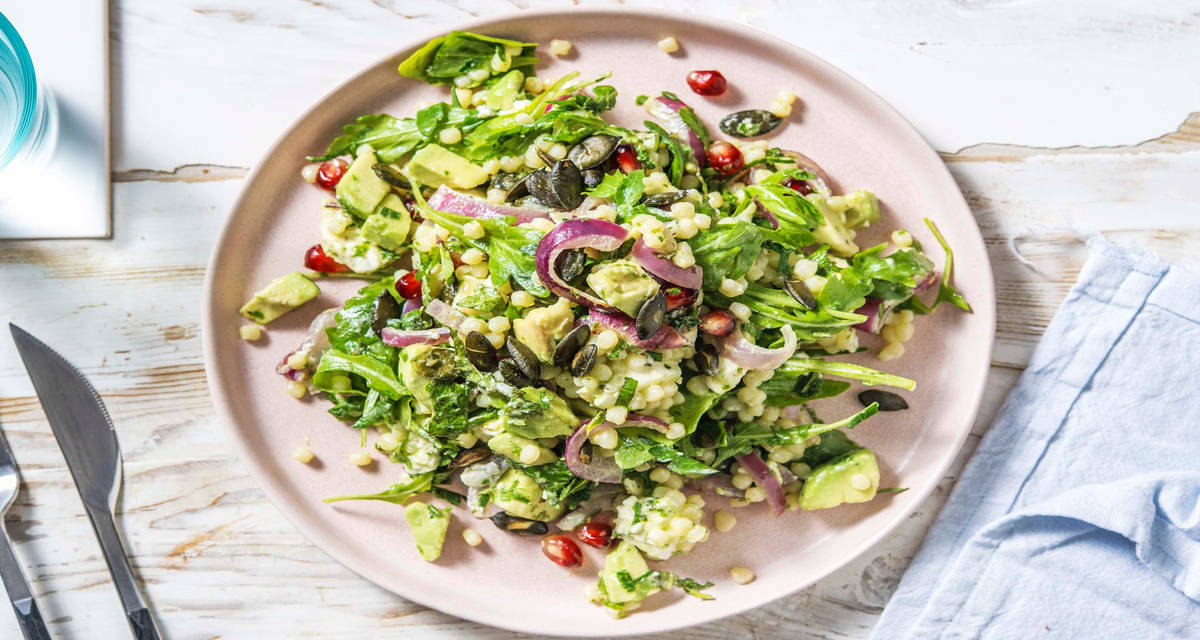 Salade couscous perlé, feta rôtie & grenade avec de l'avocat, des graines de courge et de la menthe fraîche