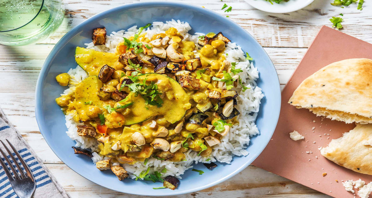 Curry d'aubergine rôtie & pois chiches servi avec un naan et des noix de cajou