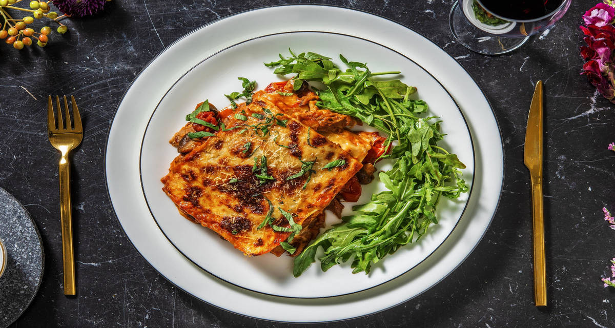 Lasagnes de confit de canard à la sauce tomate servies avec de la roquette