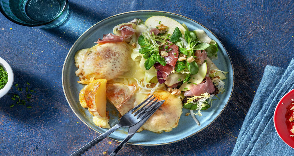 Pommes de terre gratinées au fromage à raclette avec une salade au jambon serrano, concombre et noix
