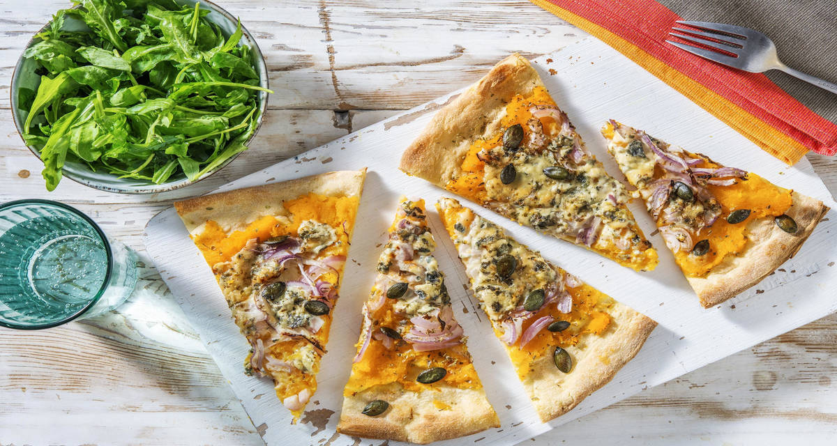 Pizza base courge et bleu d'Auvergne avec de l'origan, des oignons rouge et de la roquette