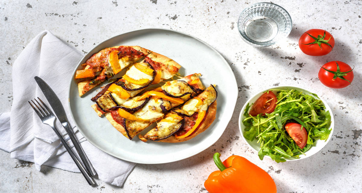 Pizza de berenjena y pimiento acompañada de ensalada de rúcula y tomate