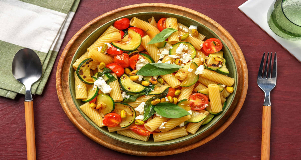 Pasta primavera zucchine, datterini e basilico con scorza di limone, formaggio greco e pistacchi