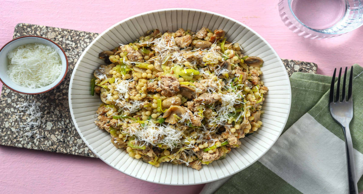 Couscous perlato salsiccia e funghi con porri rosolati e formaggio grattugiato