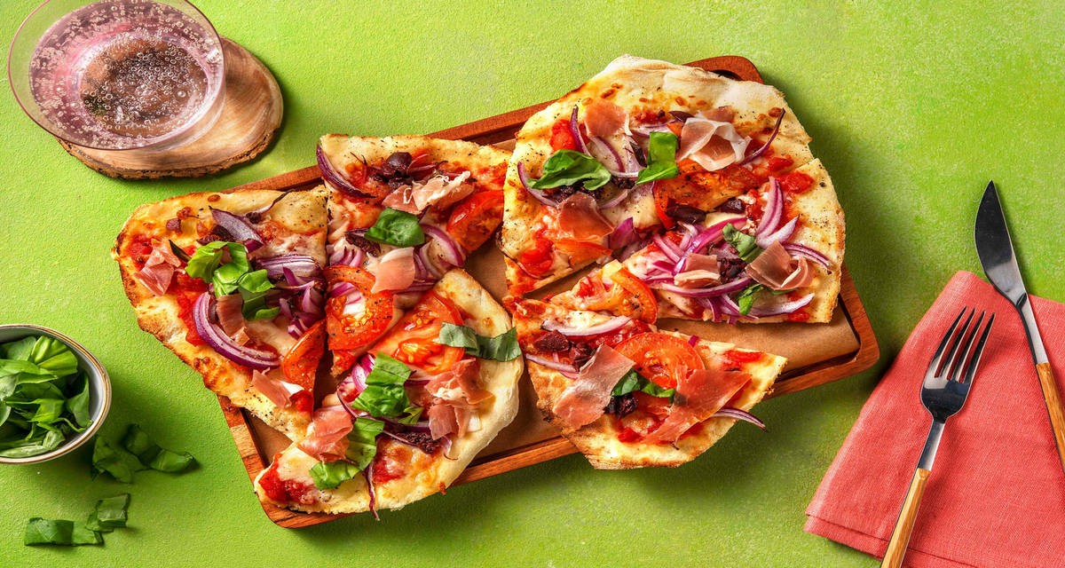 Prosciutto-naanizza med hackade oliver och färsk basilika