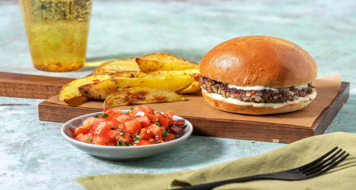 Hamburger sfizioso di carne alle erbe con patatine arrosto e insalata di pomodori