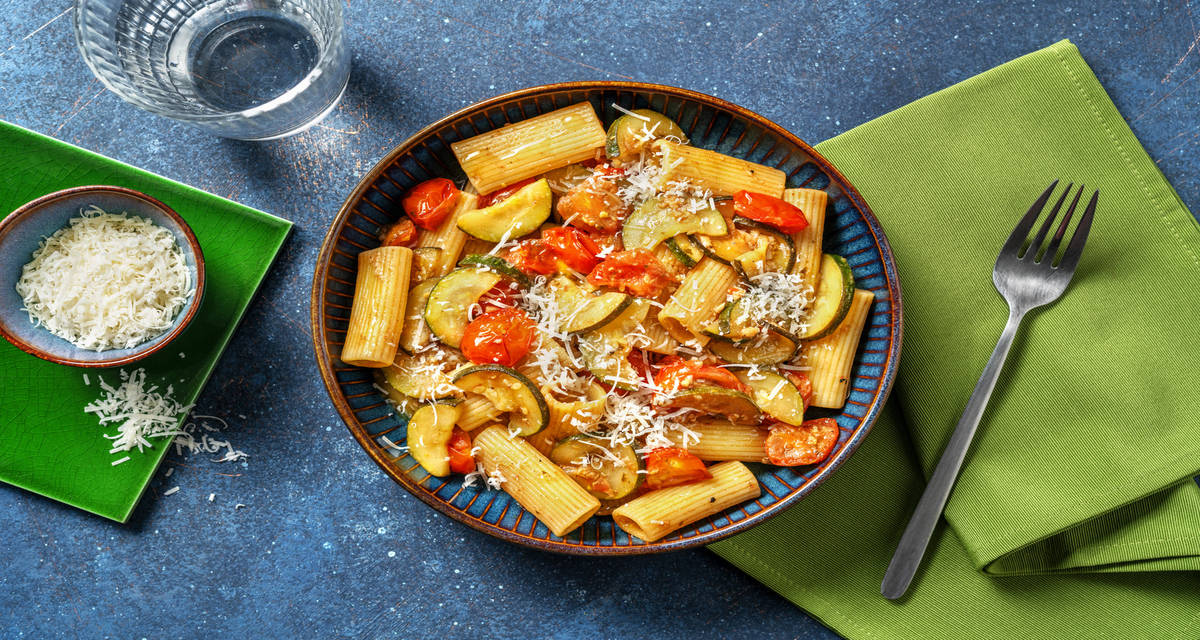 Rigatoni al pesto con calabacín acompañado de tomates cherry y queso italiano rallado