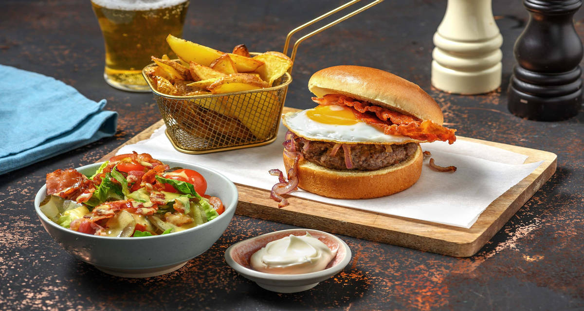 Hamburger deluxe met ontbijtspek en spiegelei op briochebroodje met truffelmayo en kerstomatensalade