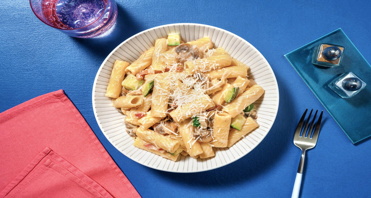 Rigatoni con bacon en salsa de queso con calabacín y champiñones salteados