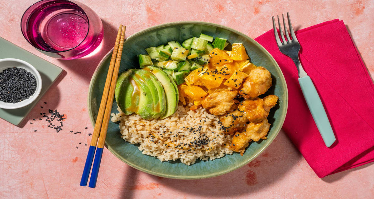 Pokébowl met gefrituurde kip en bruine rijst met avocado, appelsien en komkommer