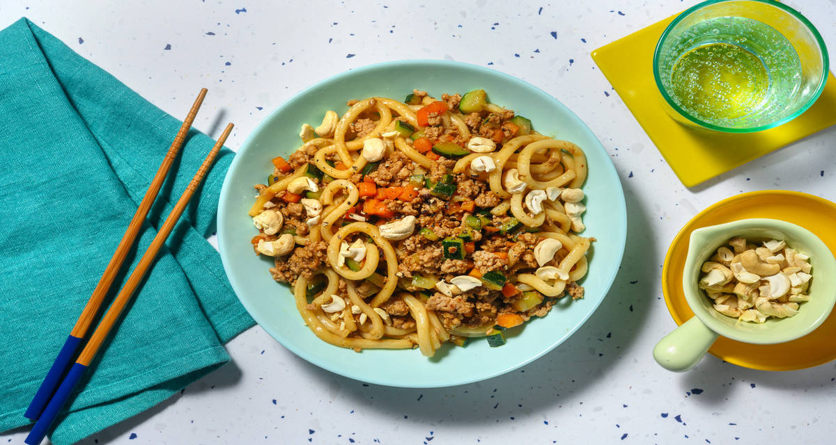 Noodles udon al ragù esotico di pollo e soia con zucchine, carote e anacardi
