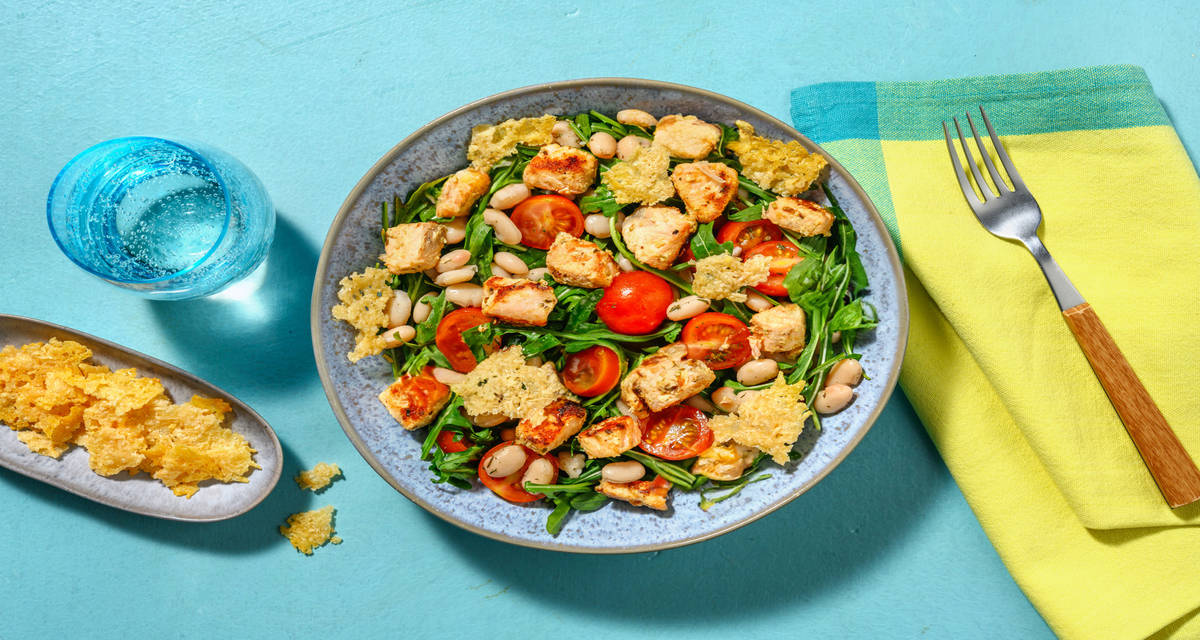 Dados de salmón con crujiente de queso sobre ensalada de rúcula, cherrys y judías blancas