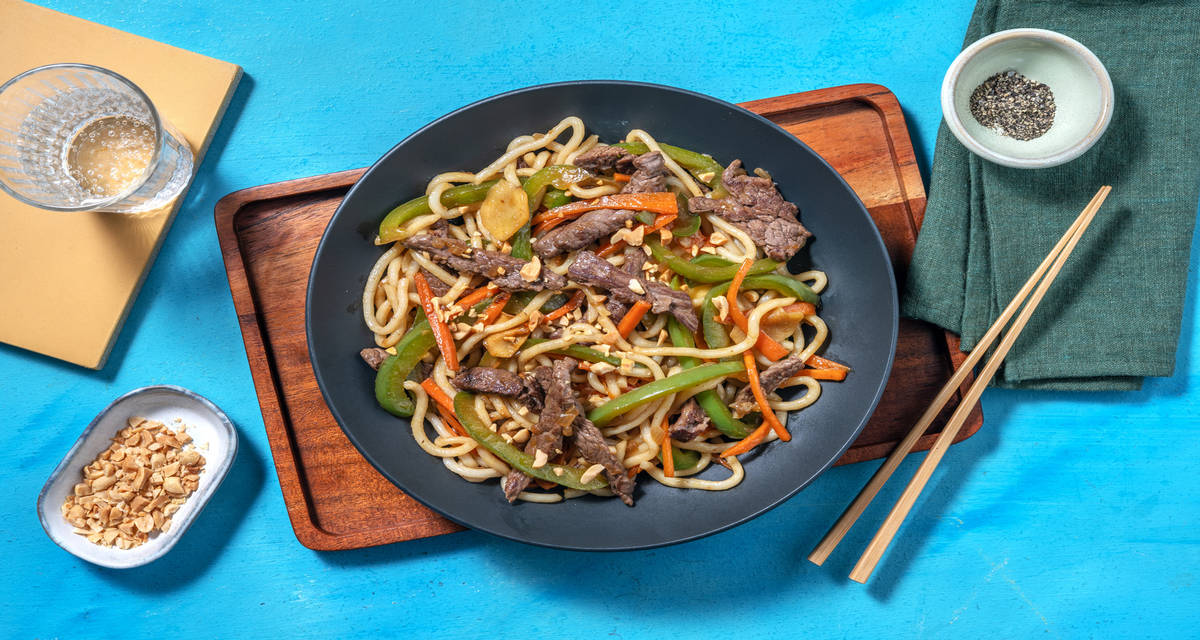 Noodles di manzo in stile asiatico con verdure saltate e arachidi