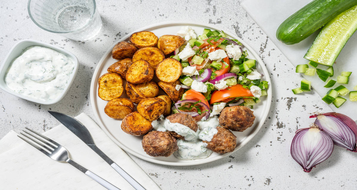Kipgehaktballetjes met Griekse salade met patatjes, yoghurtsaus en verse kruiden