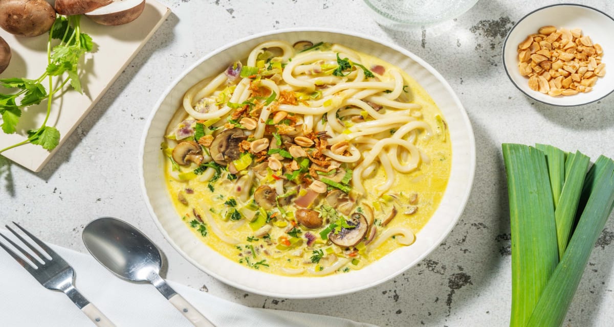 Curry-noedelsoep met kokosmelk met verse udonnoedels, koriander en pinda's-image