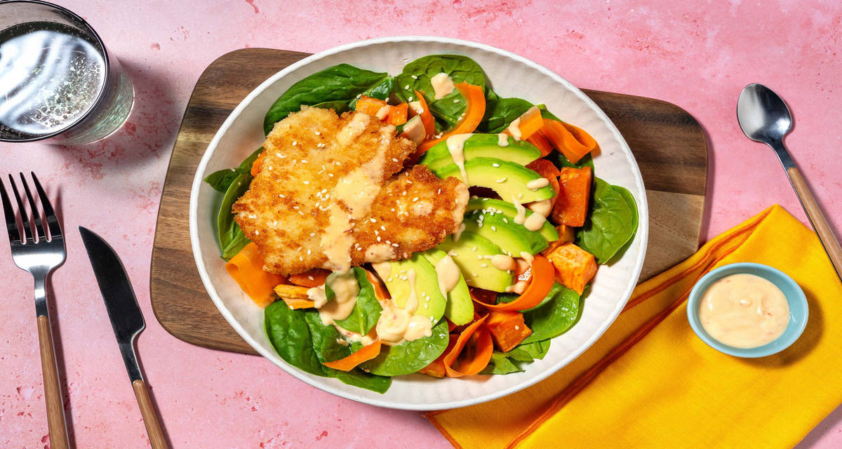 Buddha bowl au poulet pané, avocat et patate douce préparé avec des épinards, de la carotte à l'aigre-douce et une sauce crémeuse pimentée