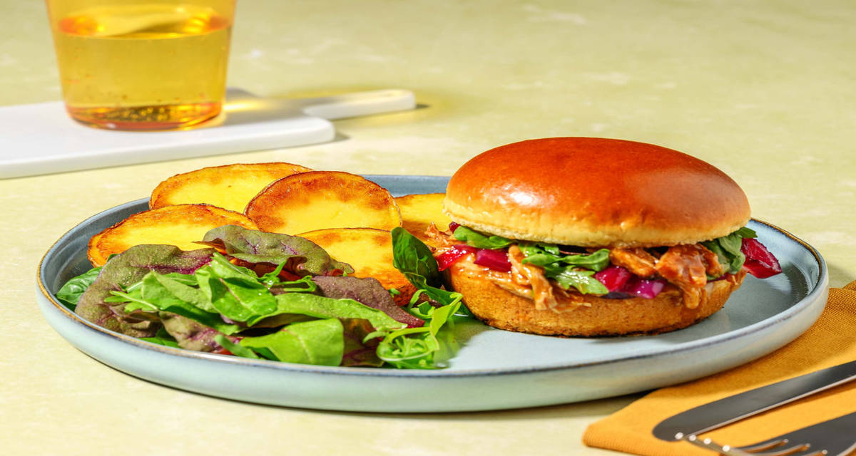 Burger gustoso al pulled pork e cheddar con cipolle dolci, patate e insalata
