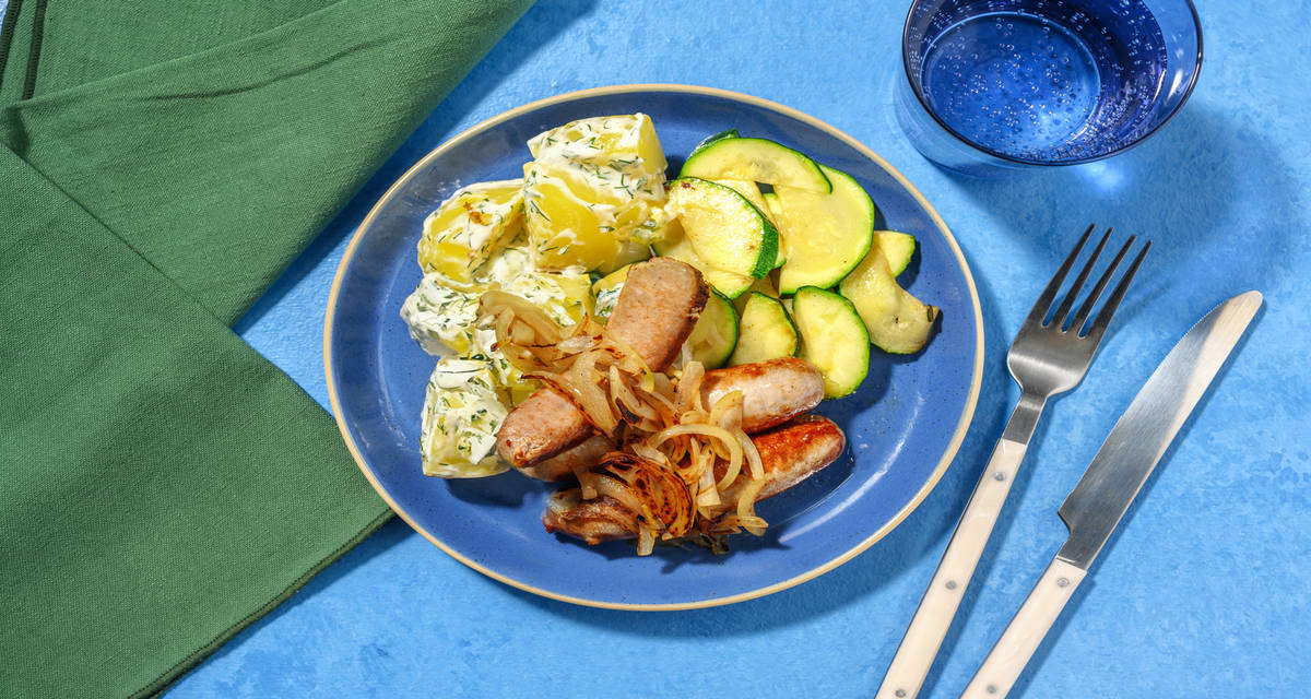 Salchichas encebolladas con patatas al eneldo y calabacín salteado
