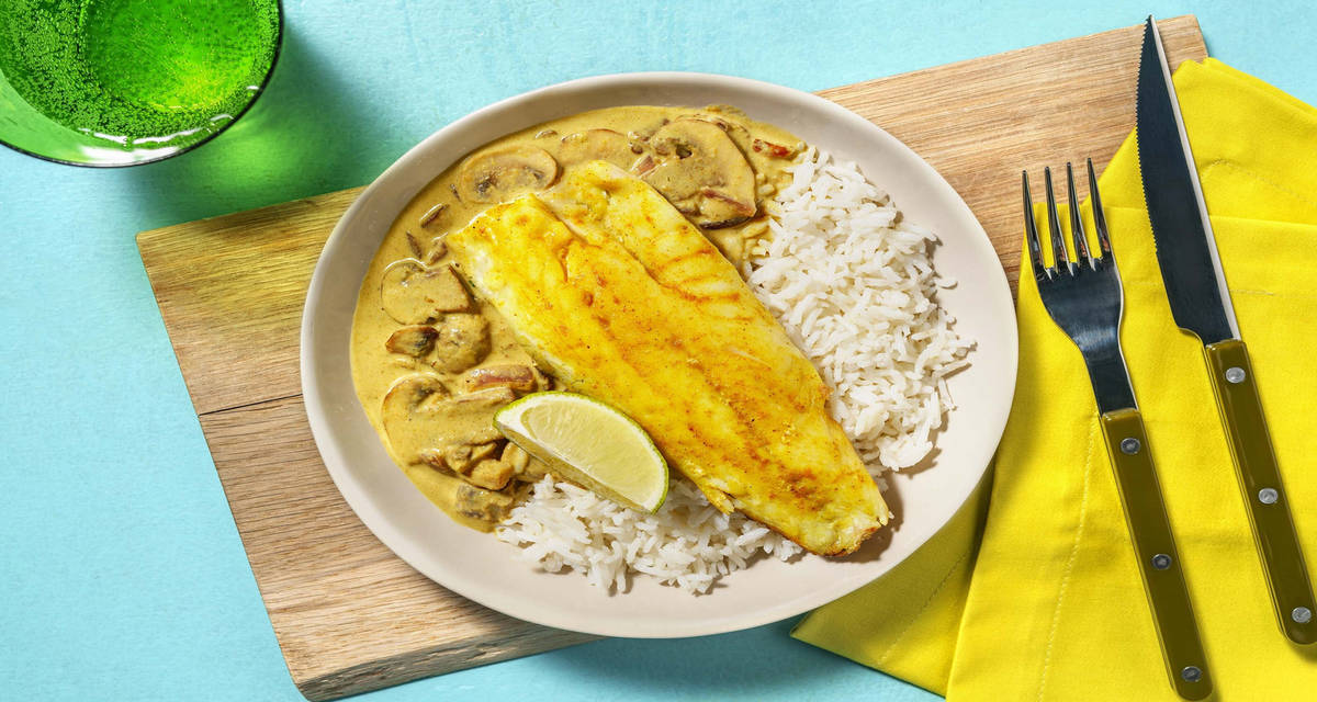 Heek in groene-currysaus met gele rijst, champignons en limoen