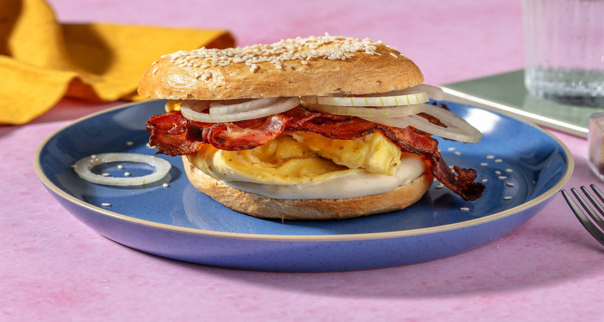 Bagel alla salsiccia e uova strapazzate con cipolla marinata e salsa alla worcester